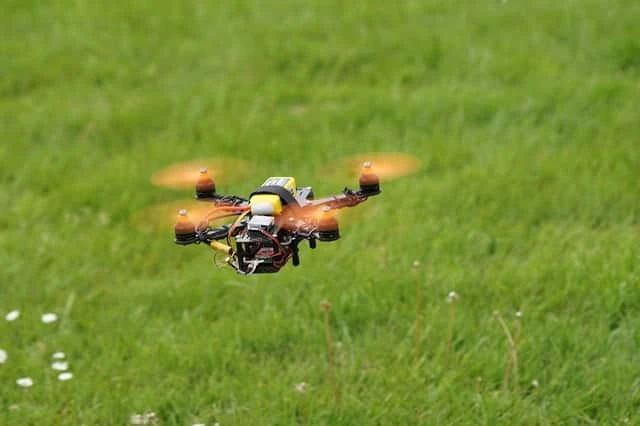 草地の上を飛行する小型マルチコプターの写真。